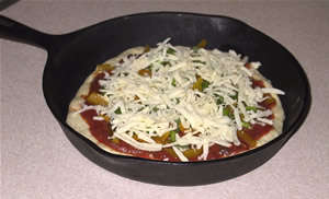 pizza in an iron skillet, ready to cook
