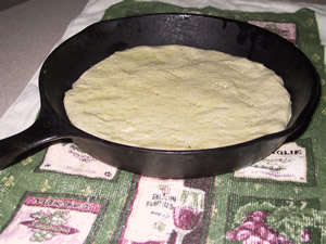 pizza dough in iron skillet, ready for toppings